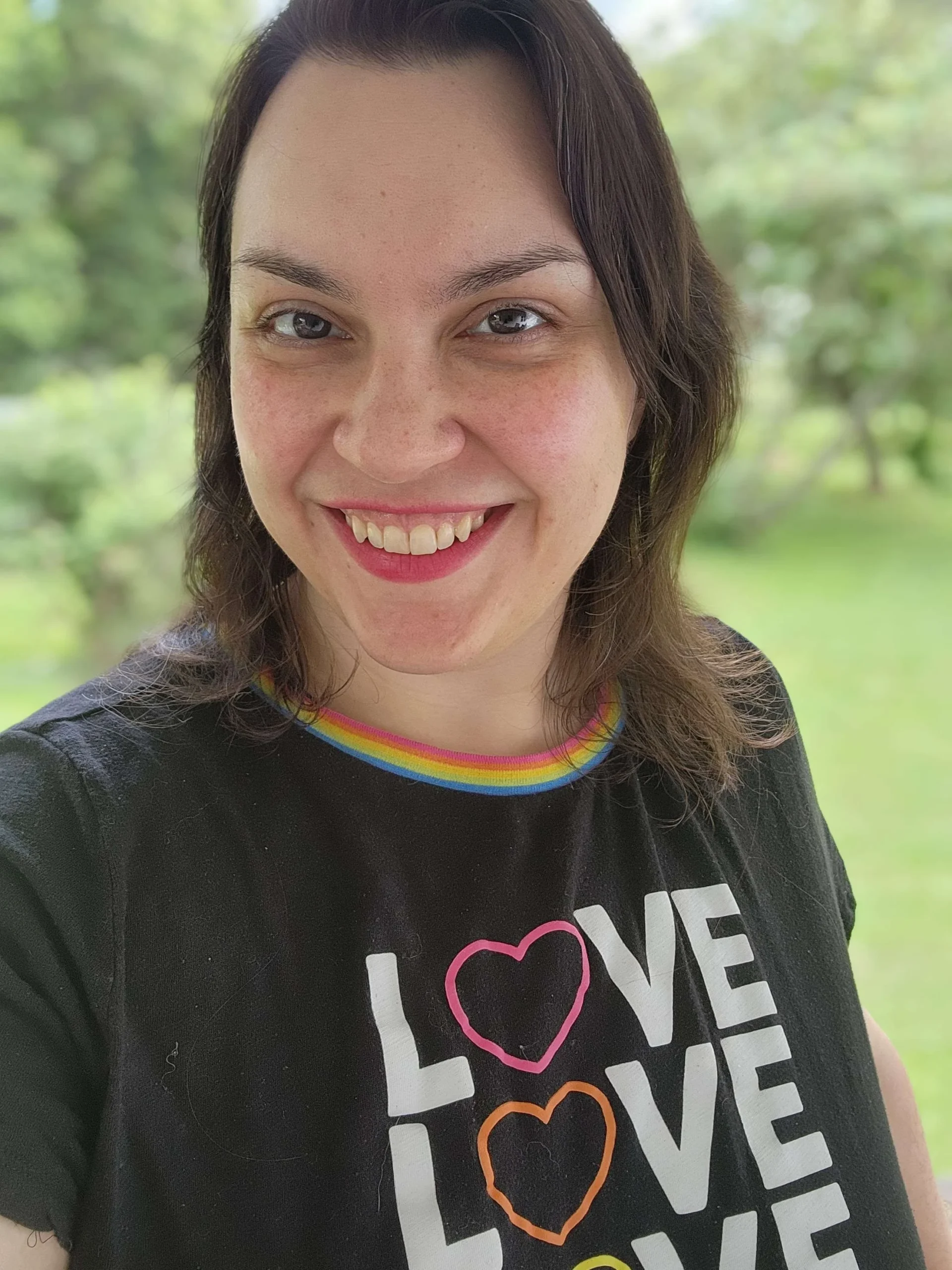 Safrianna smiling warmly at the camera wearing a Love shirt