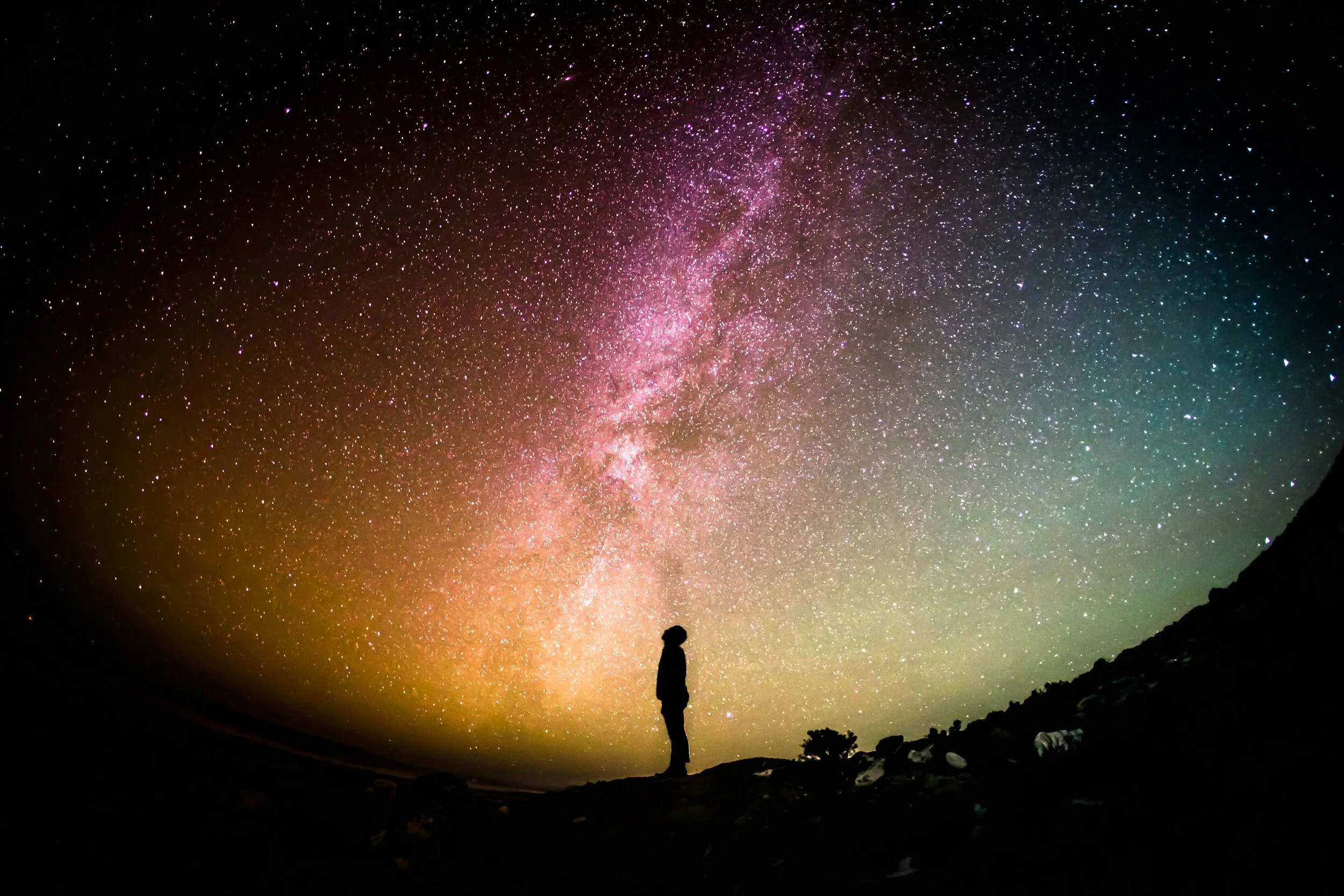 Silhouette of a person looking up at the Milky Way.