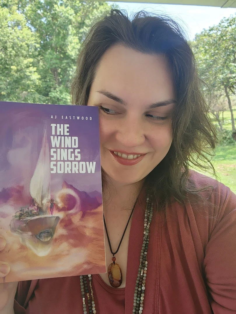 Here I am with a copy of my latest novel— The Wind Sings Sorrow — feeling genuinely happy for following the fullness of my dreams of being a speculative fiction author despite years of being told it wasn’t the responsible thing to do with my life.